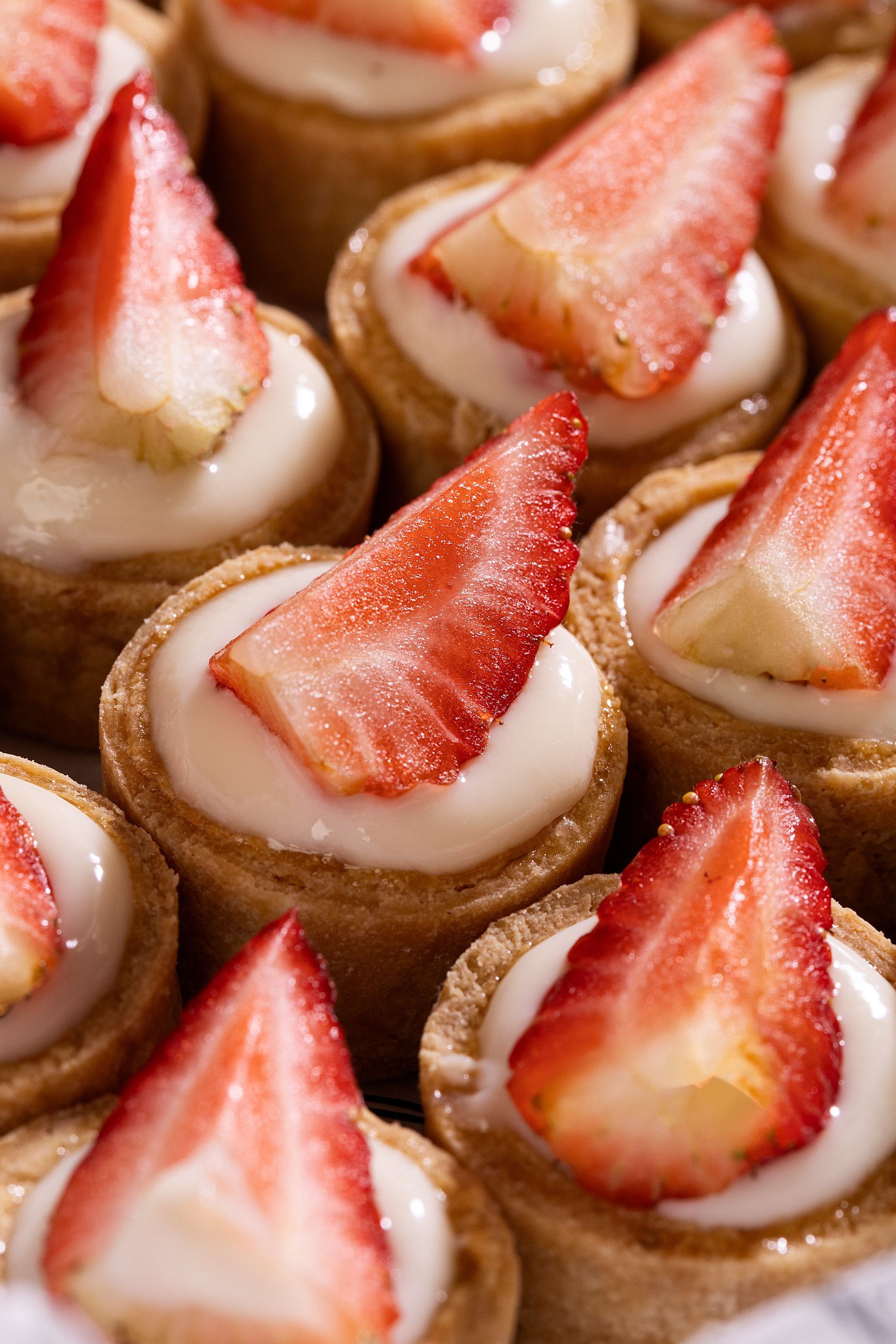 Mini tortinhas recheadas com creme e fatias de morango fresco.