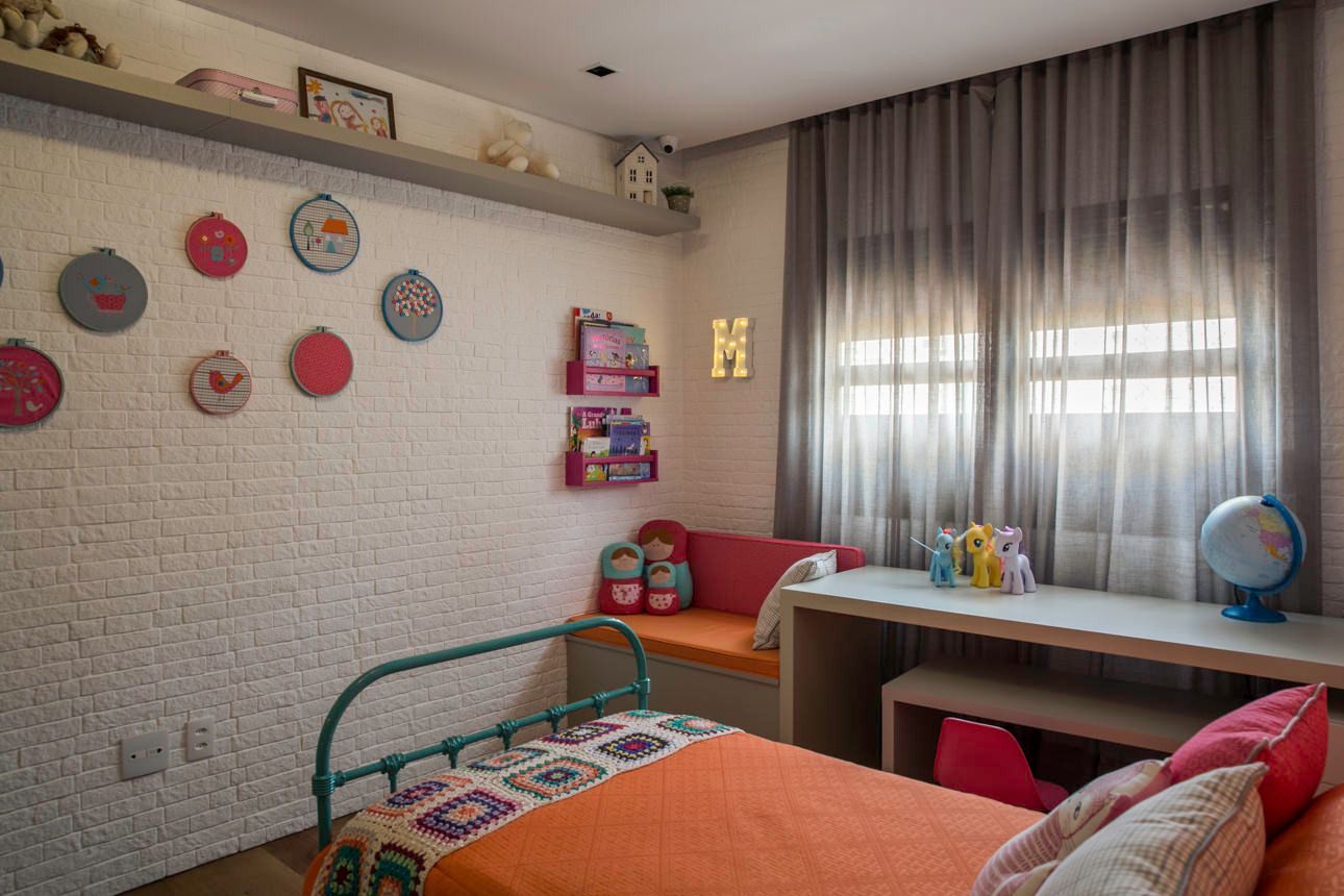 Quarto infantil iluminado com arte na parede, cama, escrivaninha perto da janela e cortinas.