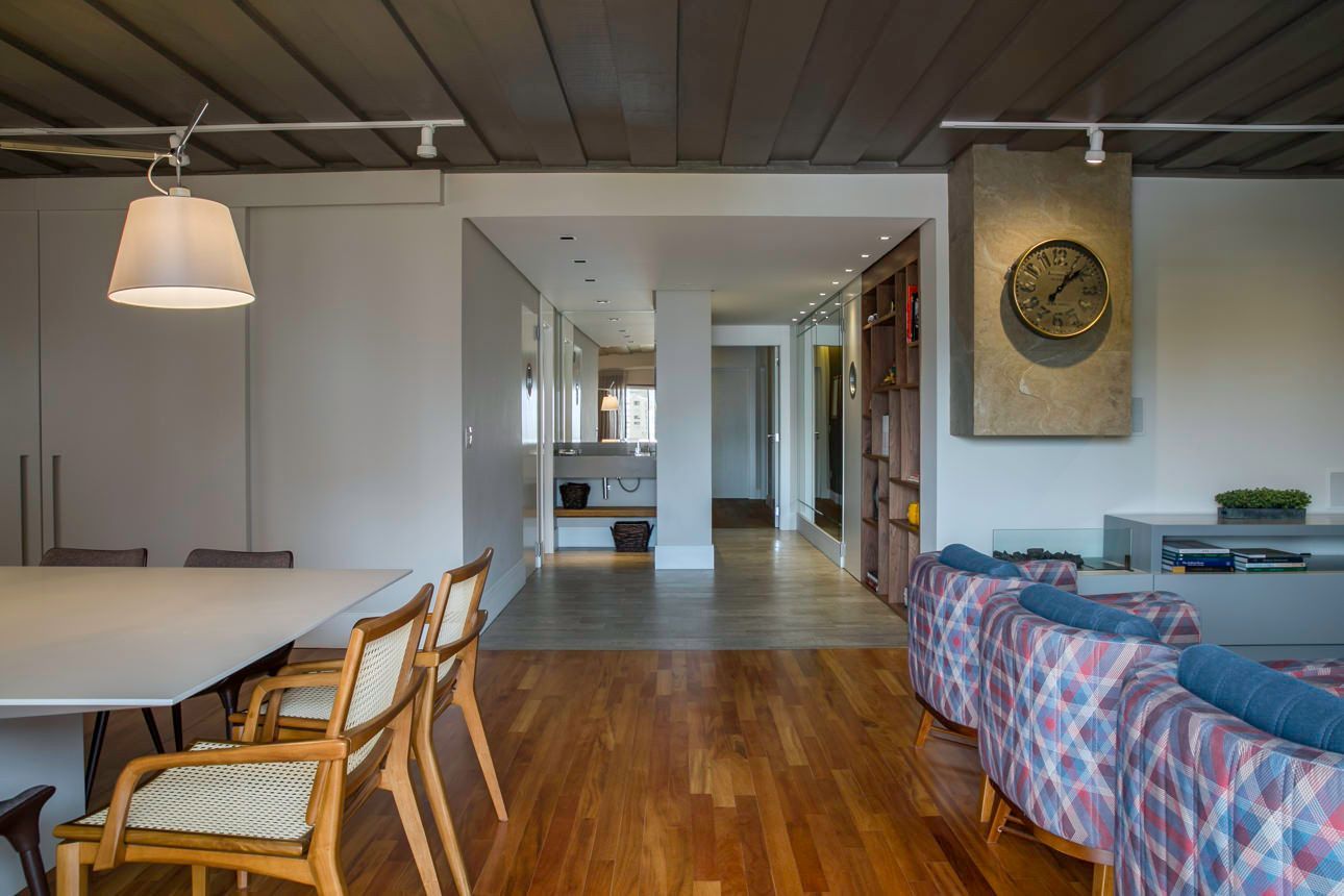 Sala de estar e jantar moderna em conceito aberto, com piso de madeira, luminárias pendentes e um sofá com estampa azul.