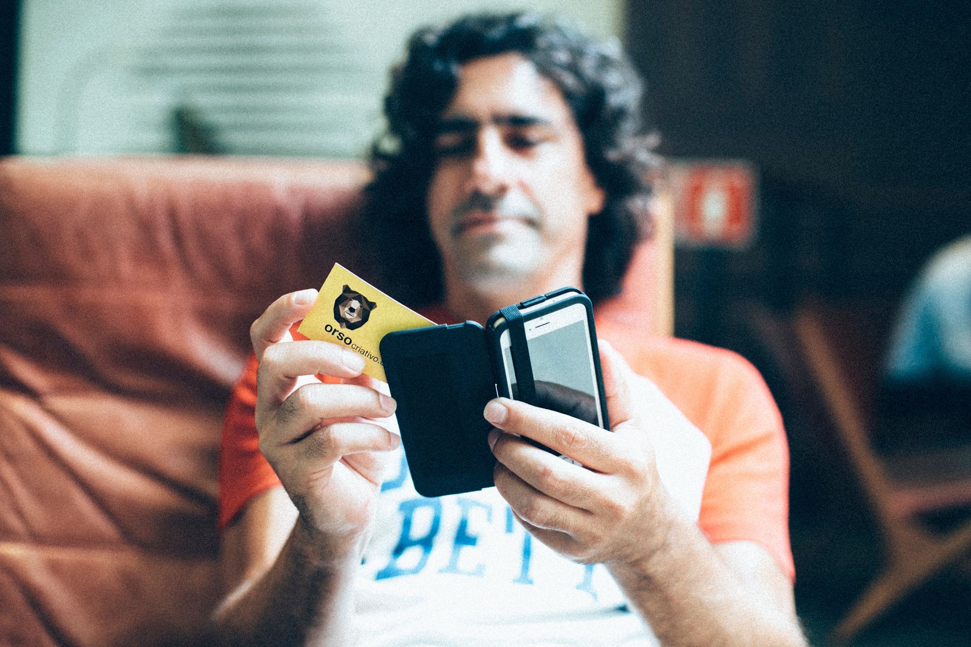Pessoa sentada em um sofá segurando um console de videogame portátil e um cartucho de jogo.