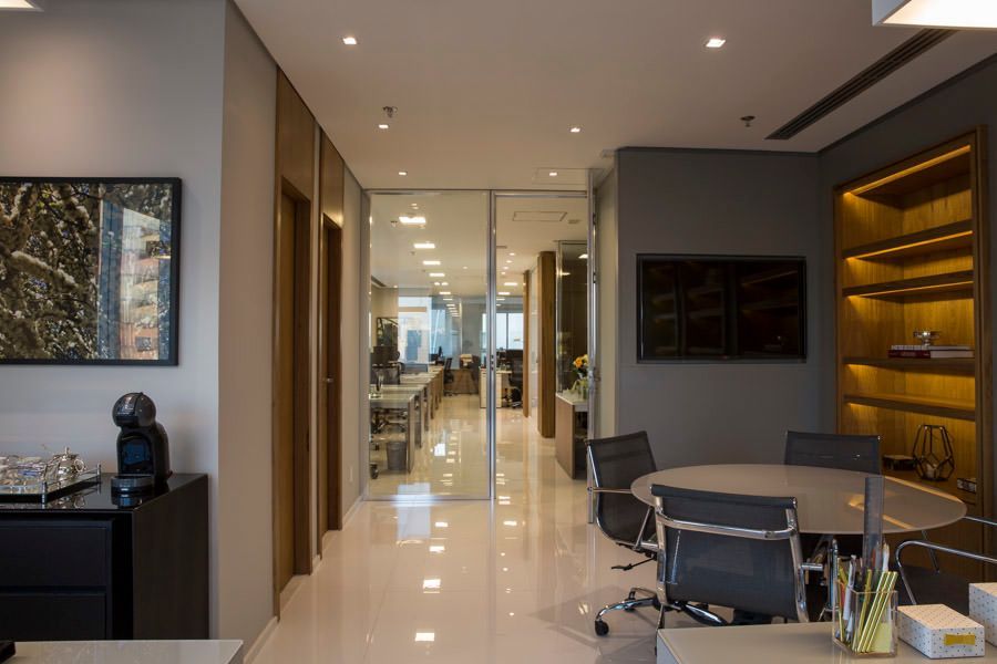 Corredor de escritório moderno com piso brilhante, iluminação embutida e mesa de conferência em uma sala de reuniões elegante.