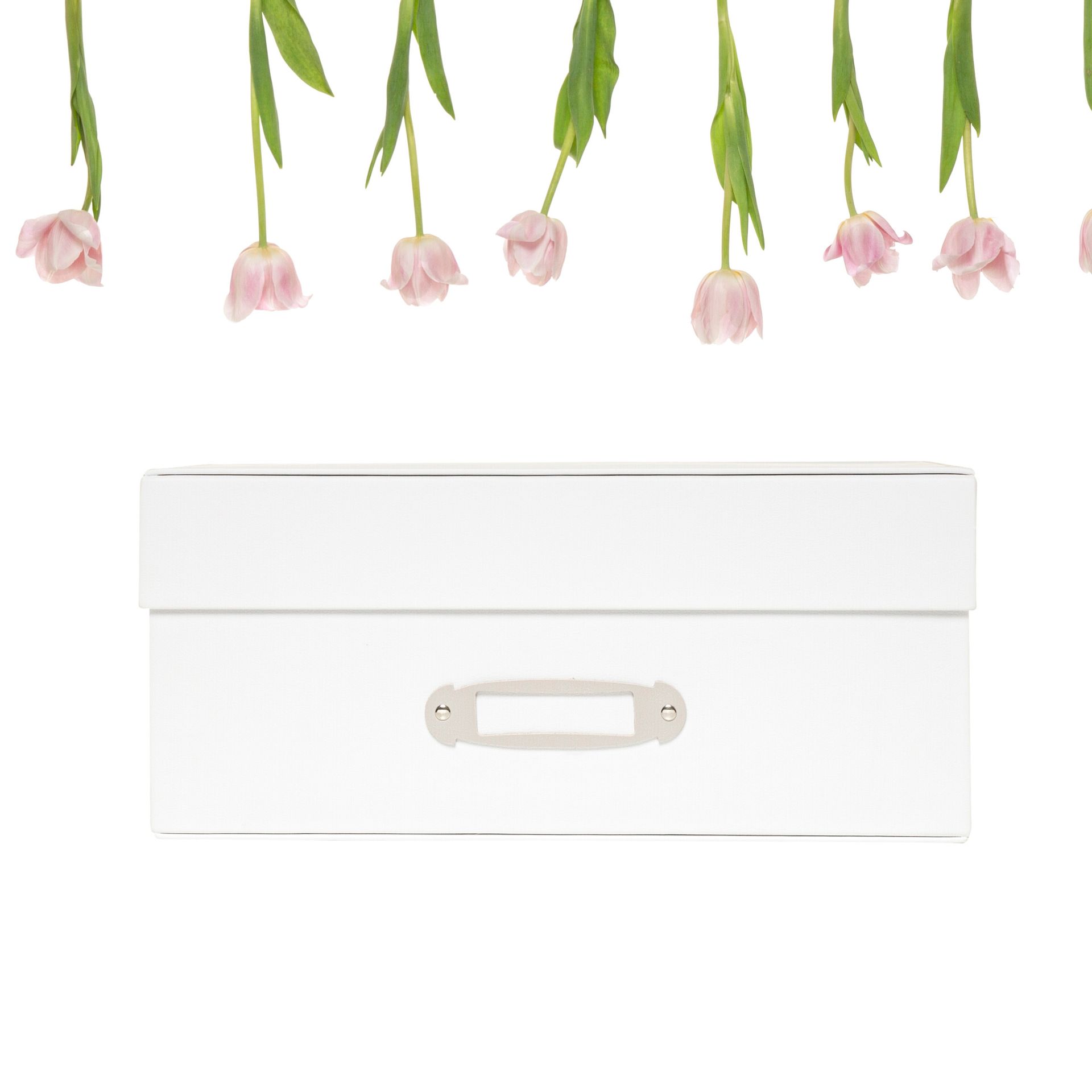 Caixa de armazenamento branca sob flores rosa penduradas em um fundo branco liso.