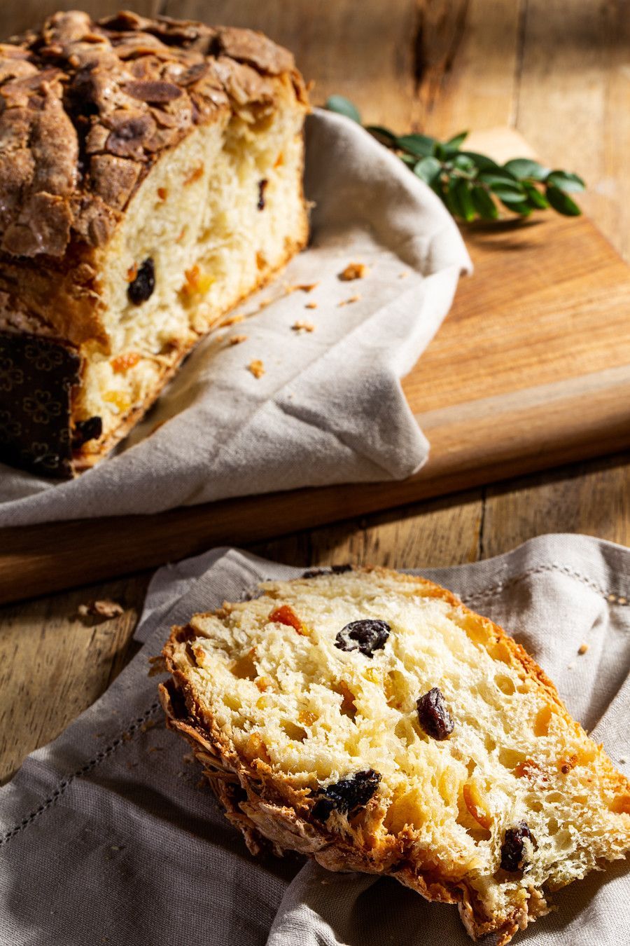 Fatias de bolo de frutas secas e nozes sobre uma tábua de madeira com um guardanapo de pano.