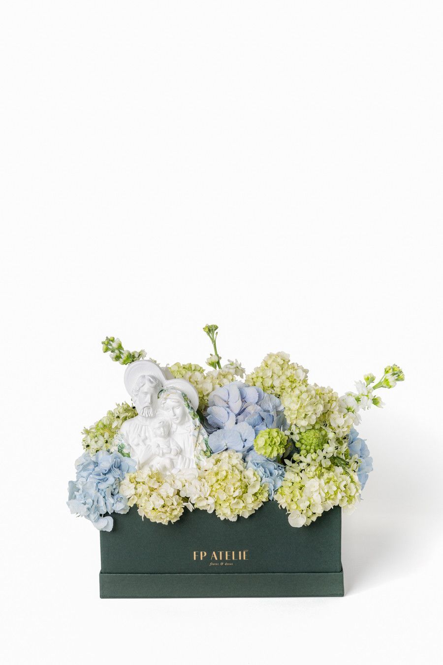 Arranjo de flores em tons pastel em uma caixa verde-escura sobre um fundo branco.