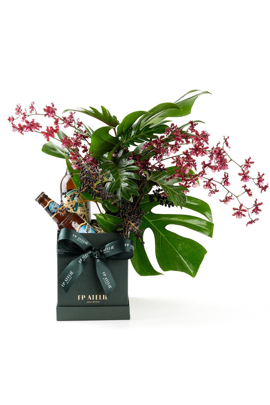 Arranjo de orquídeas rosa em um vaso verde-escuro com folhagem verde exuberante sobre fundo branco.
