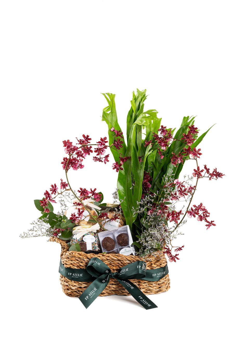 Cesta de flores cor-de-rosa e folhagem verde com um laço decorativo.