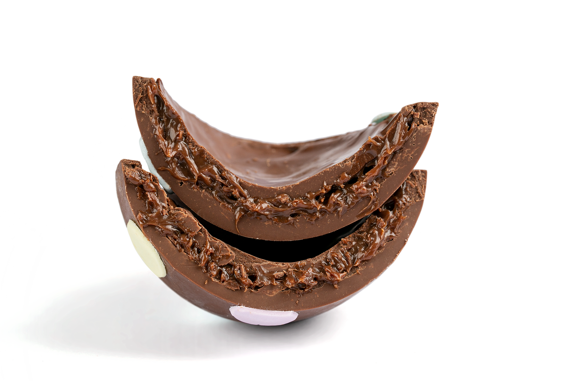 Duas metades de sobremesa de chocolate com recheio cremoso sobre fundo branco.