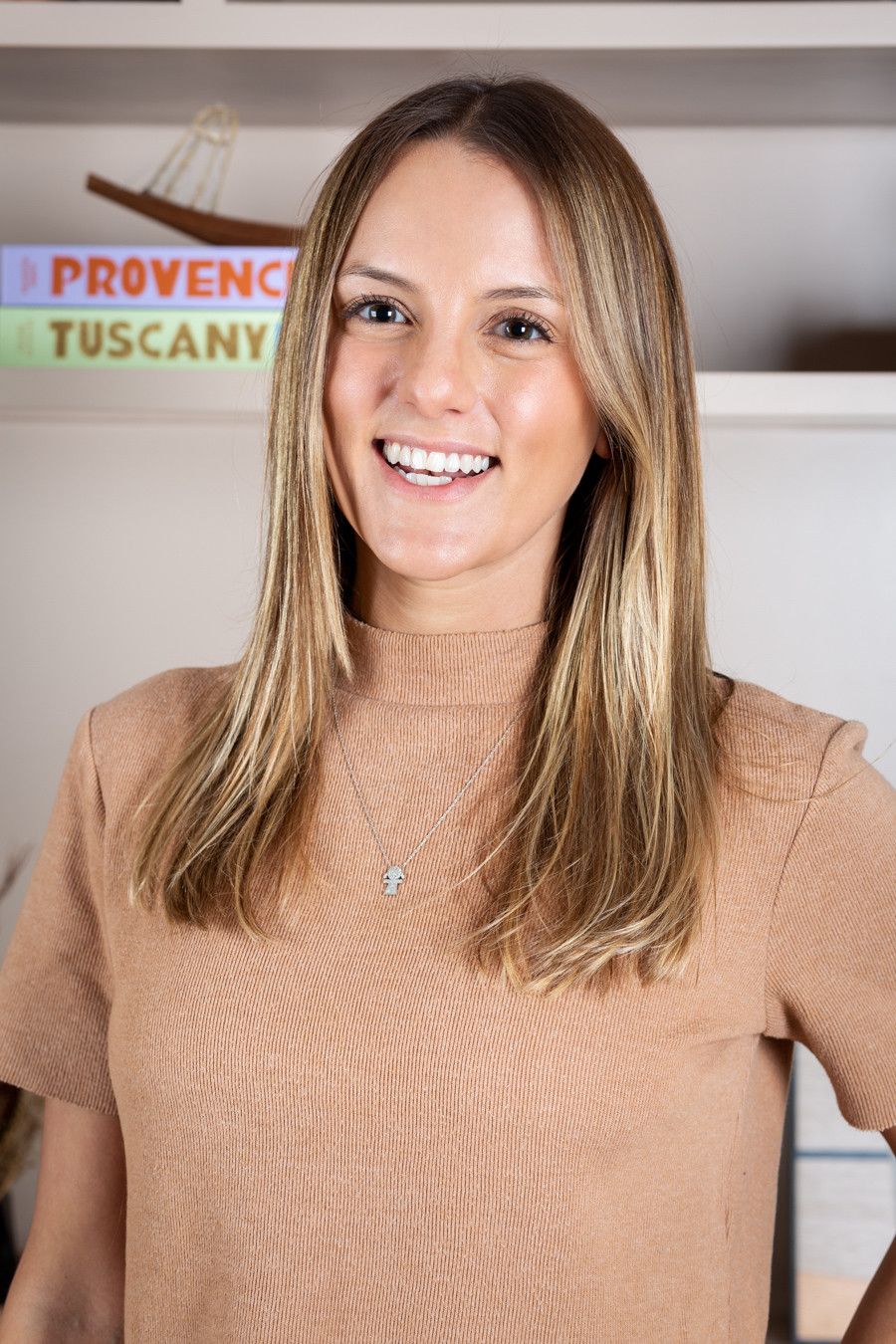 Mulher sorridente de suéter bege em pé dentro de uma escada, com placas indicando