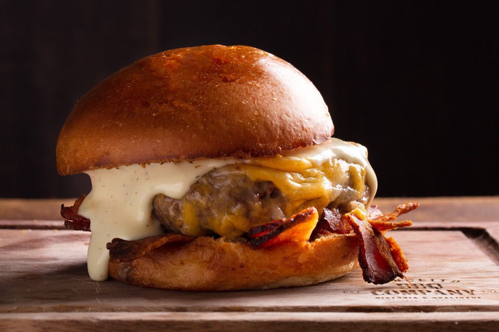 Cheeseburger com queijo derretido e bacon em uma tábua de madeira