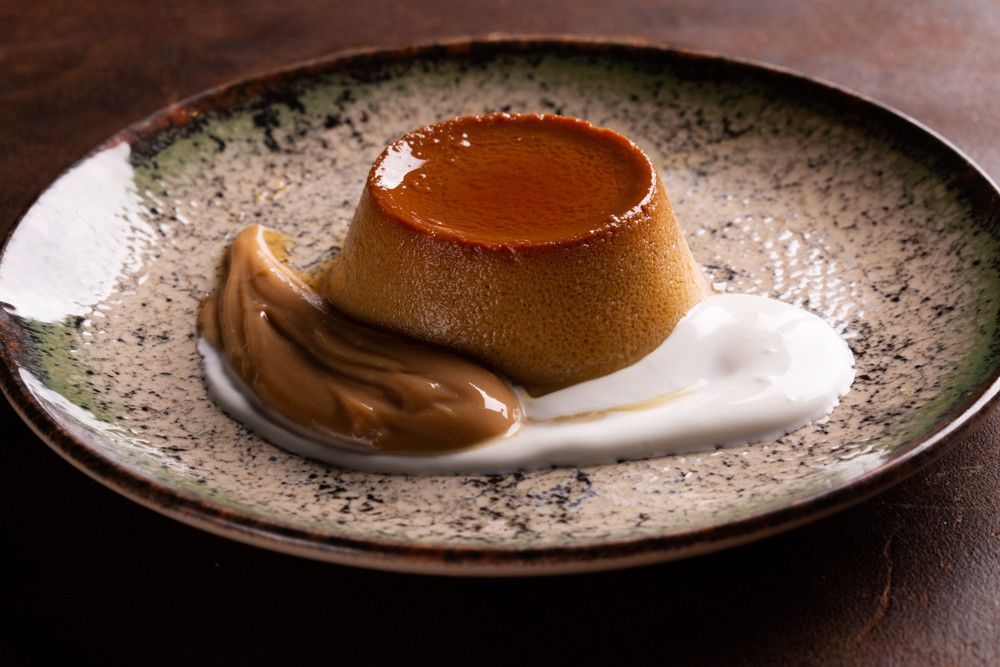 Pudim de caramelo com chantilly e calda de caramelo em um prato salpicado