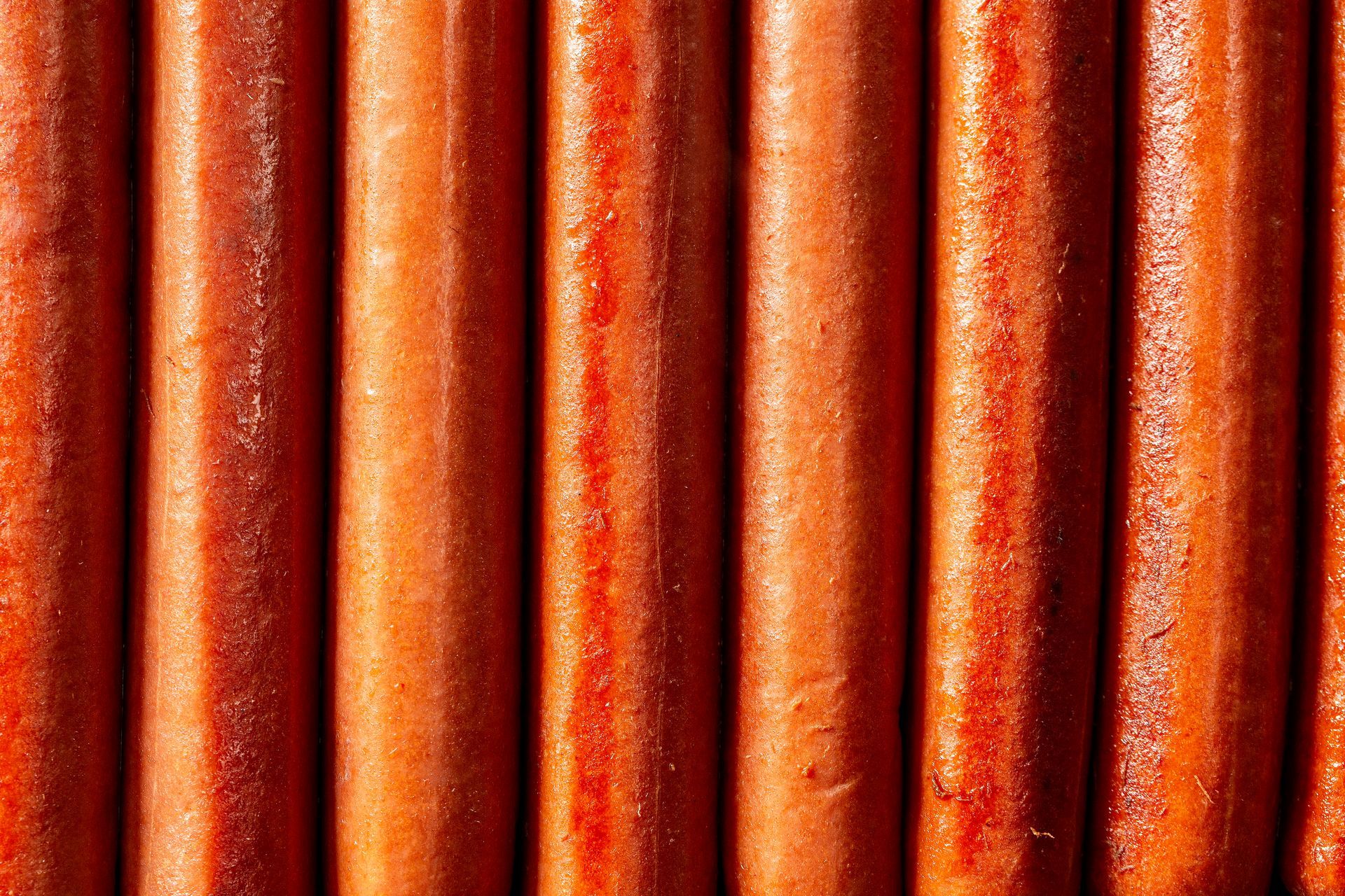 Detalhe de painéis metálicos corrugados vermelho-alaranjados com ranhuras verticais.