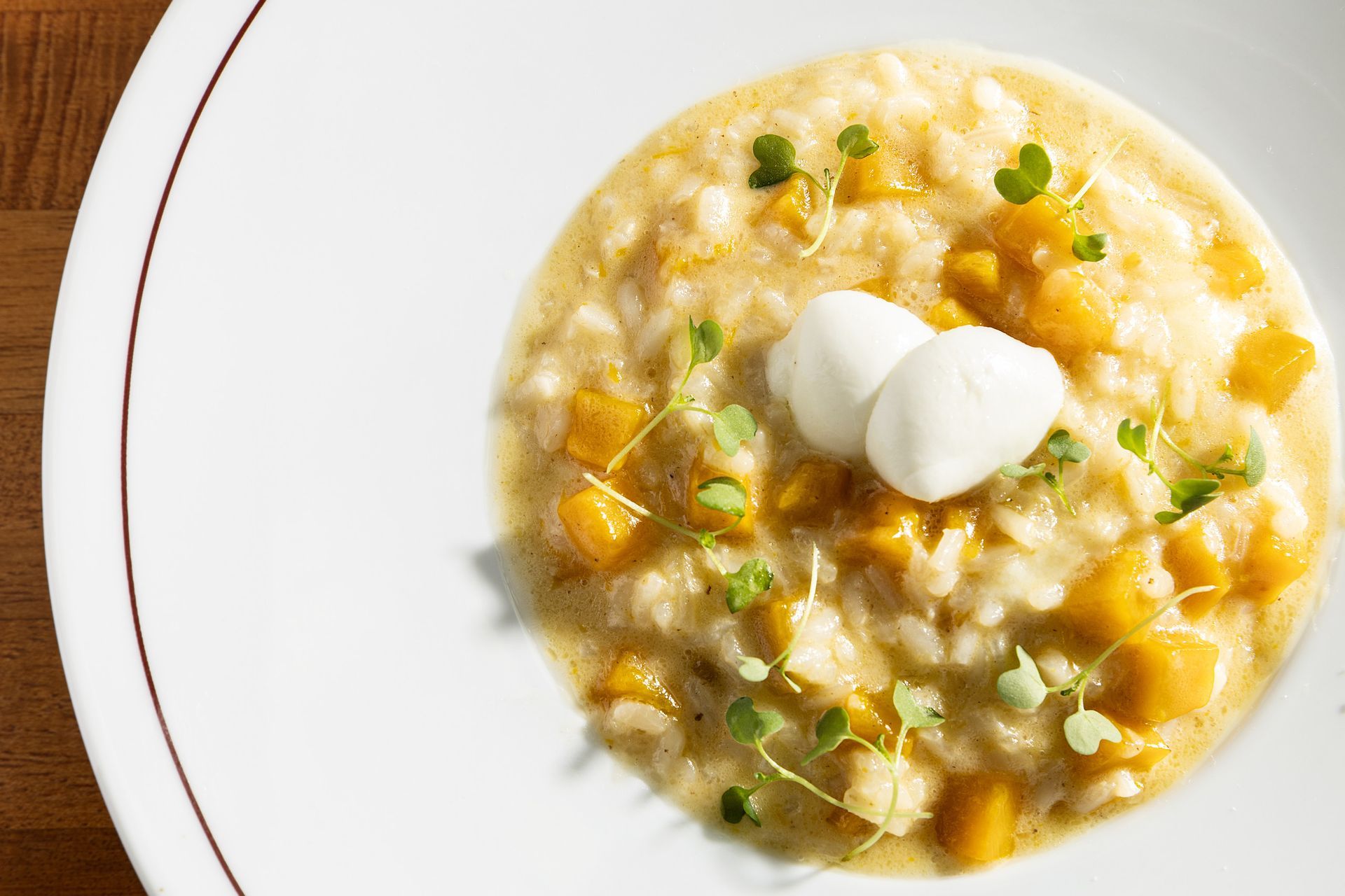 Sopa cremosa com duas colheradas de creme de leite, ervas e milho, servida em um prato branco.