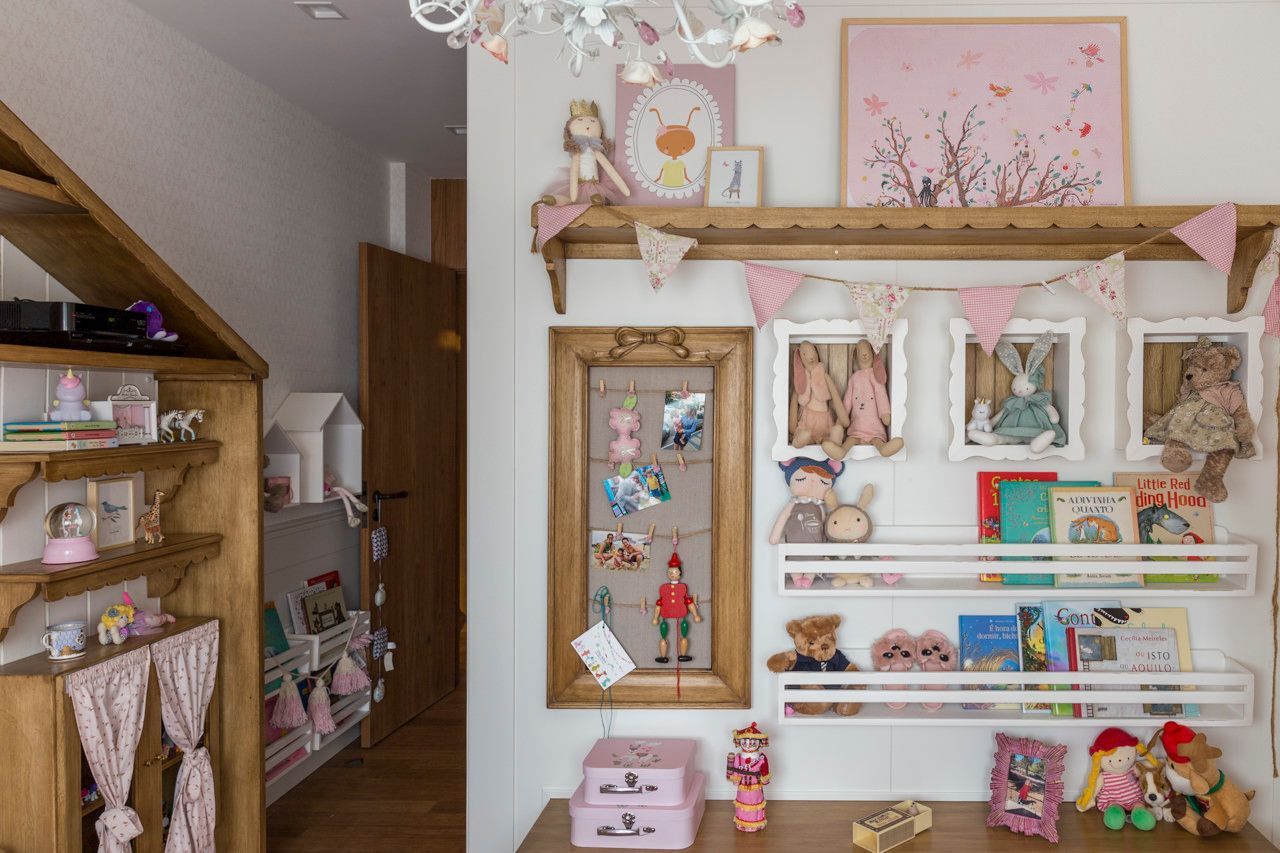 Sala de exibição de bonecas em tons pastel com prateleiras, brinquedos e decoração rosa.