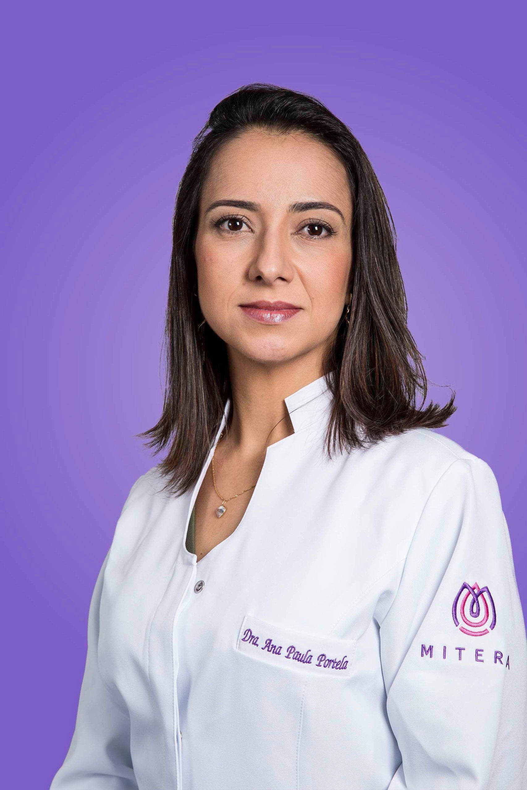 Mulher profissional de jaleco branco posando contra um fundo roxo.