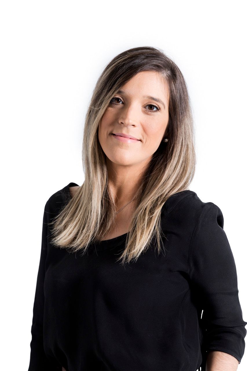 Mulher com cabelos na altura dos ombros e blusa preta, posando contra um fundo branco.