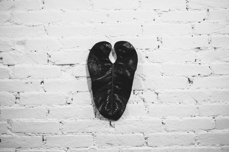 Sapatos pretos pendurados em uma parede de tijolos brancos.