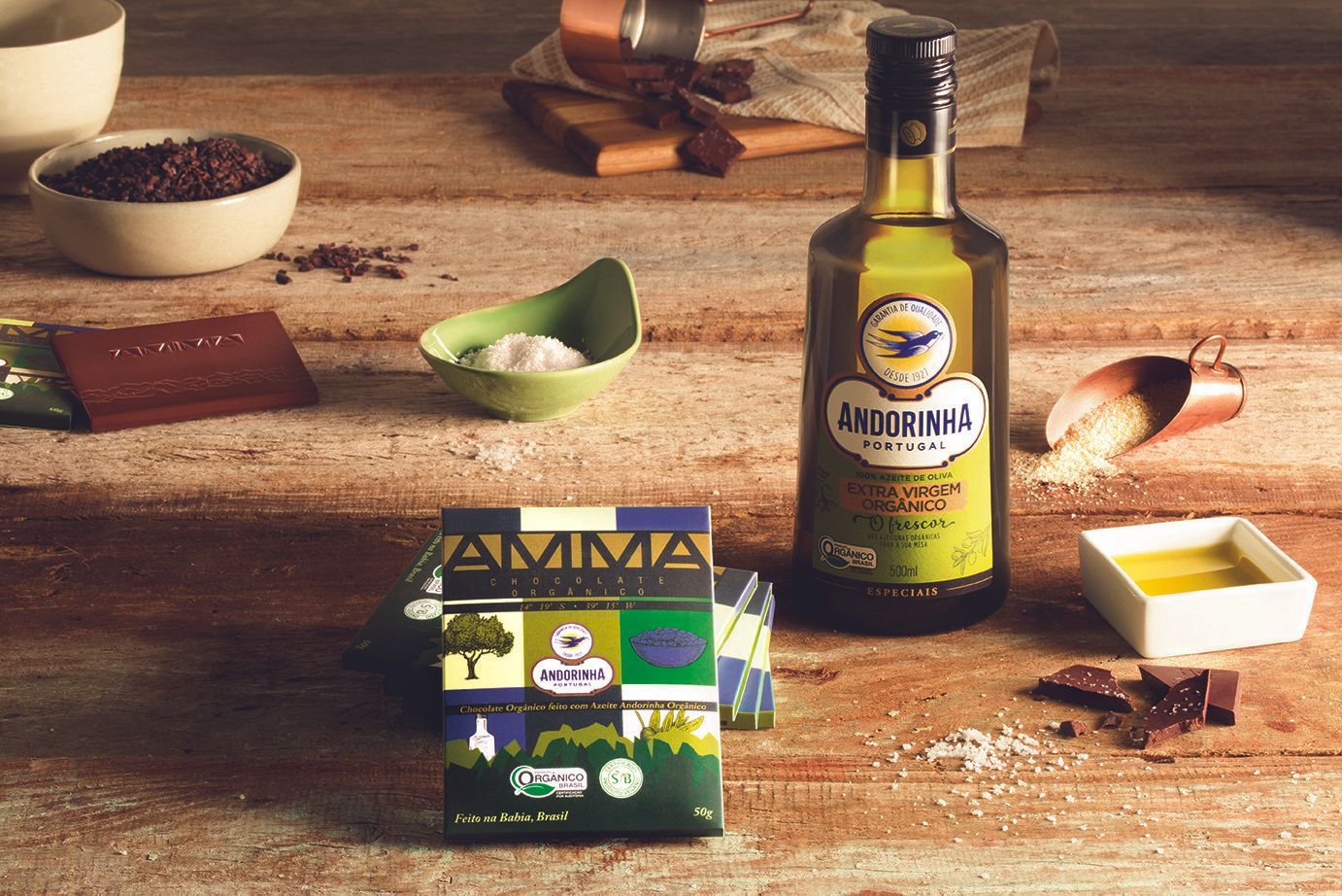Garrafa de azeite com limões, azeitonas e outros ingredientes sobre uma mesa rústica de madeira.
