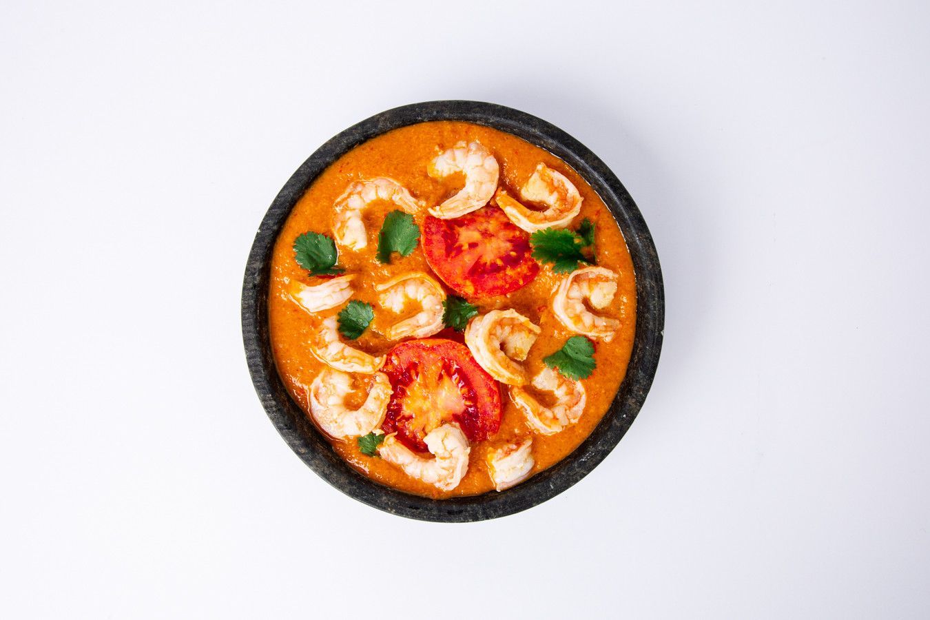 Vista de cima de um prato de massa com camarão ao molho de laranja, tomates-cereja e manjericão.