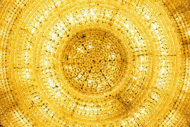 Padrão mandala circular dourado com anéis concêntricos de detalhes texturizados intrincados.