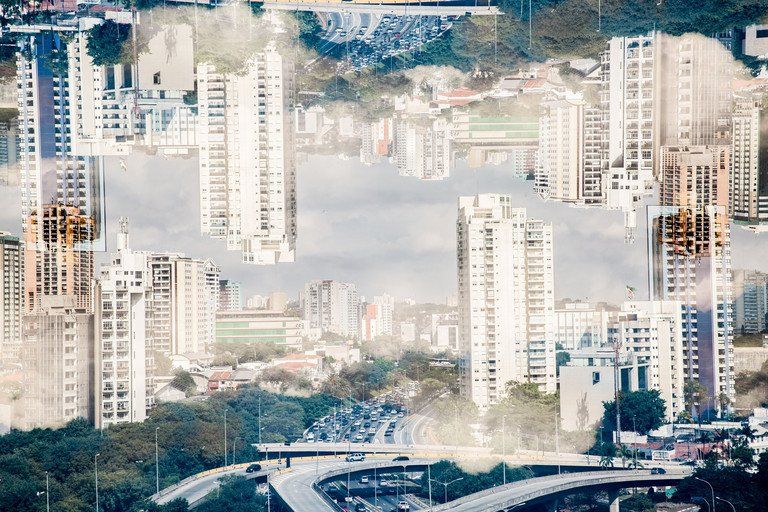 Horizonte abstrato espelhado da cidade com altos edifícios brancos, árvores e um céu enevoado.