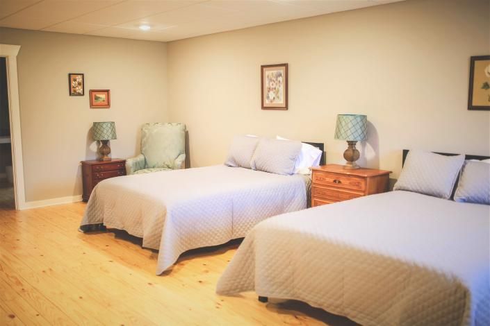 Bedroom with two neatly made twin beds, wooden nightstands, lamps, and framed wall art.