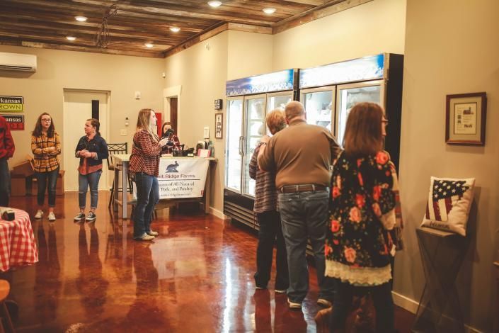 People viewing artwork in a polished gallery with wood floors and framed pieces on the walls