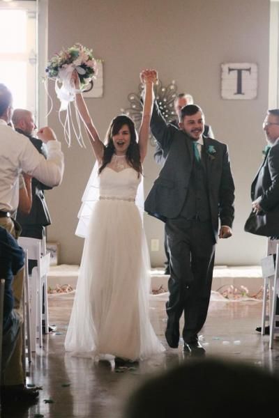 Bride and groom walking down the aisle, holding a bouquet and smiling at their wedding ceremony.