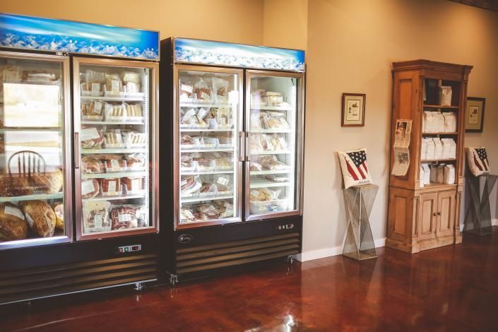 Display of assorted items in lit glass cabinets next to a wooden brochure rack in a lobby.