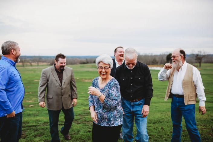 Five people chatting outdoors in a grassy field on an overcast day