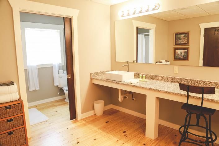 Spacious bathroom with granite vanity, large mirror, wicker storage, and a doorway to a toilet area.