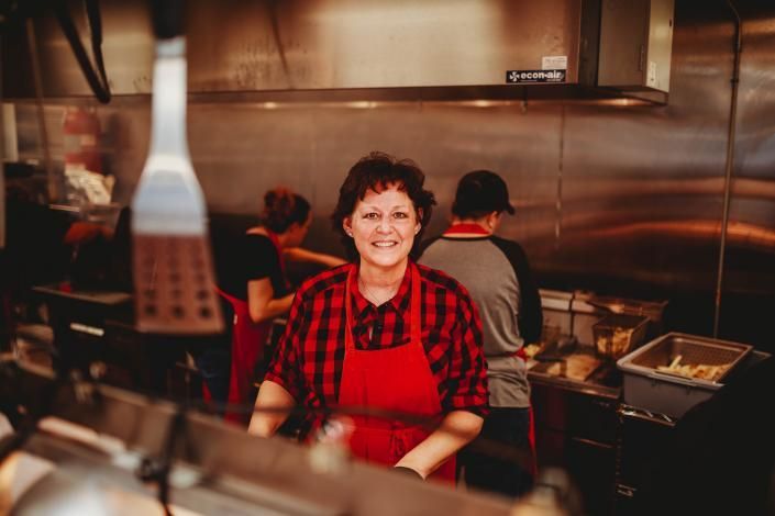 Smiling cook in red apron at a busy restaurant kitchen counter
