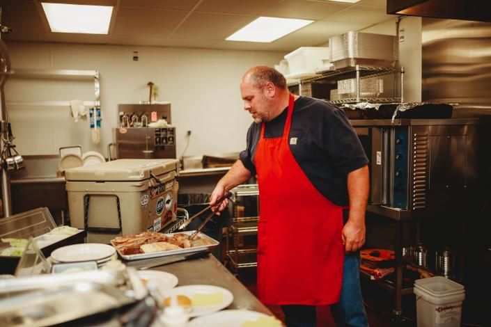 Chef in a red apron cooking in a busy commercial kitchen