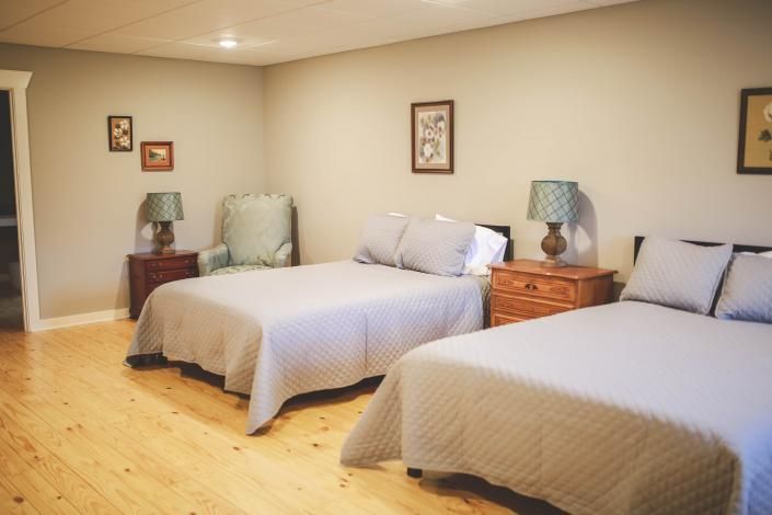 Bedroom with two neatly made twin beds, wooden nightstands, and soft beige walls and decor.