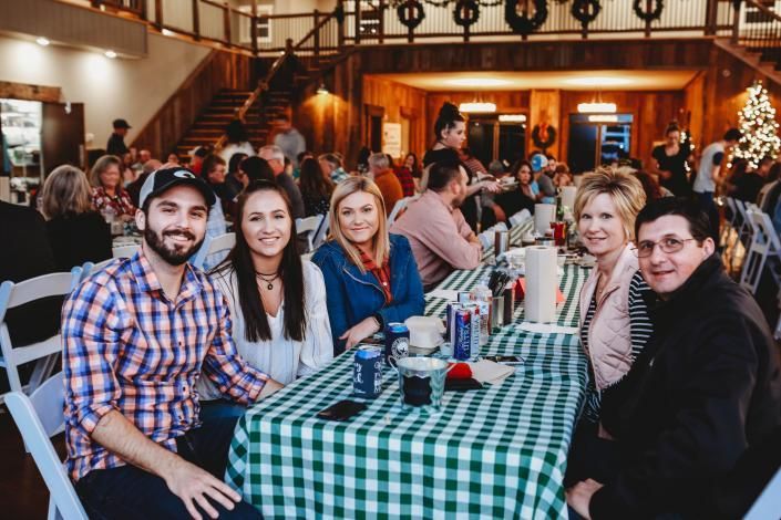 Five people seated at a checkered table in a cozy restaurant, smiling toward the camera.