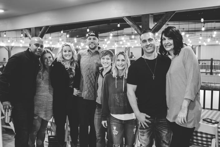 Group of seven people posing together indoors, smiling in a casual restaurant or event space.