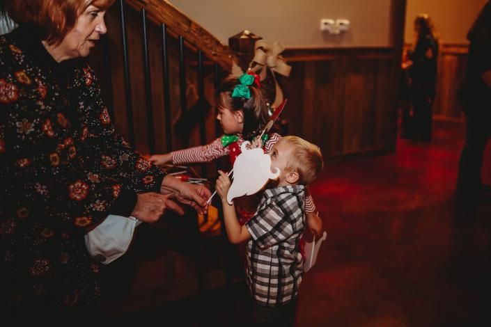 Child in plaid holding hands with an adult in a dim hallway, with a staircase in the background.