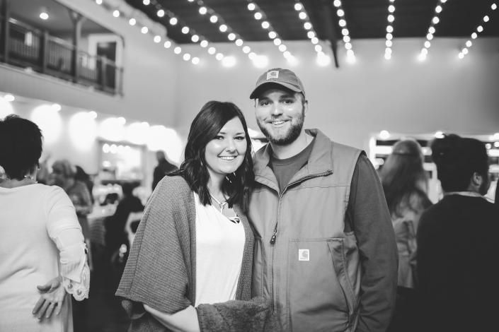 Smiling couple posing together at an indoor event with string lights overhead