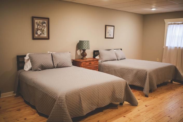Bedroom with two twin beds, wooden floors, and a small nightstand between them