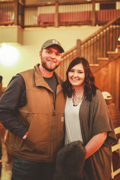 Smiling couple standing indoors in a warmly lit wooden lobby or staircase area