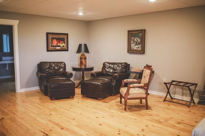 Empty living room with leather chairs, a lamp, framed art, and a wooden floor