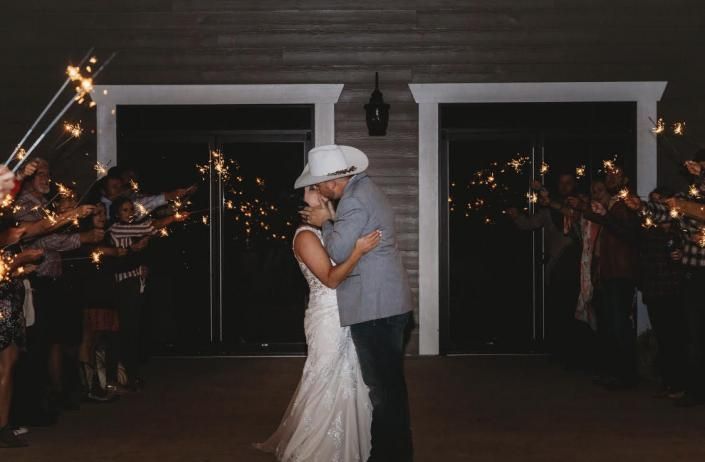 Bride and groom in a white hat share a dance at a dimly lit wedding reception