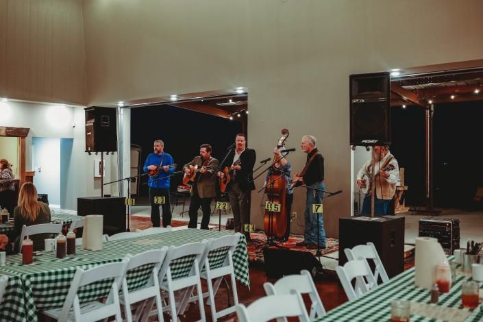 Live band performing indoors on a small stage beside tables and chairs in a banquet hall
