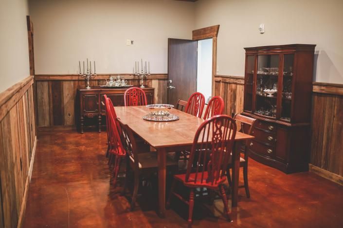 Dining room with a wooden table, red chairs, and a dark cabinet along the wall.