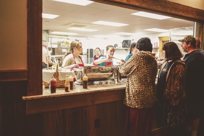 Customers standing at a café counter ordering drinks under warm indoor lighting