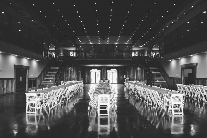 Black-and-white wedding venue with rows of white chairs facing a central aisle and staircase backdrop