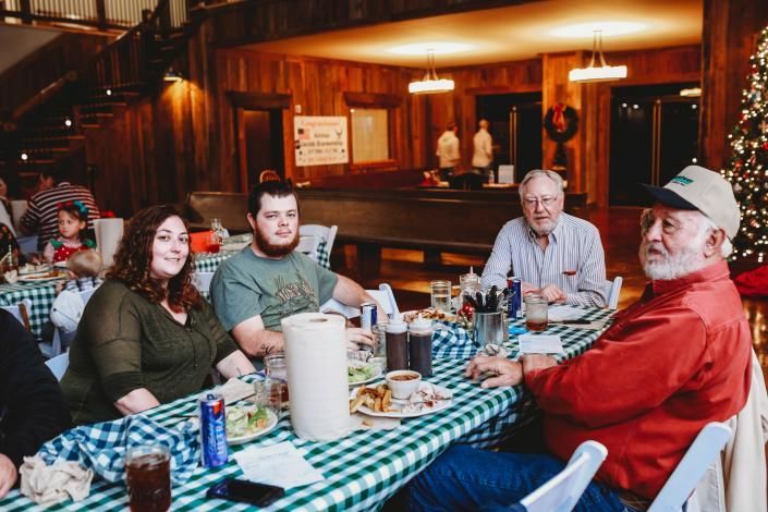 Group seated at a checkered table in a cozy wood-paneled restaurant, sharing a meal and drinks.
