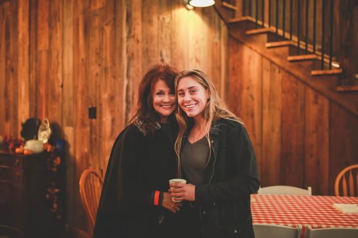 Two people smiling and posing together in a wood-paneled room with warm lighting