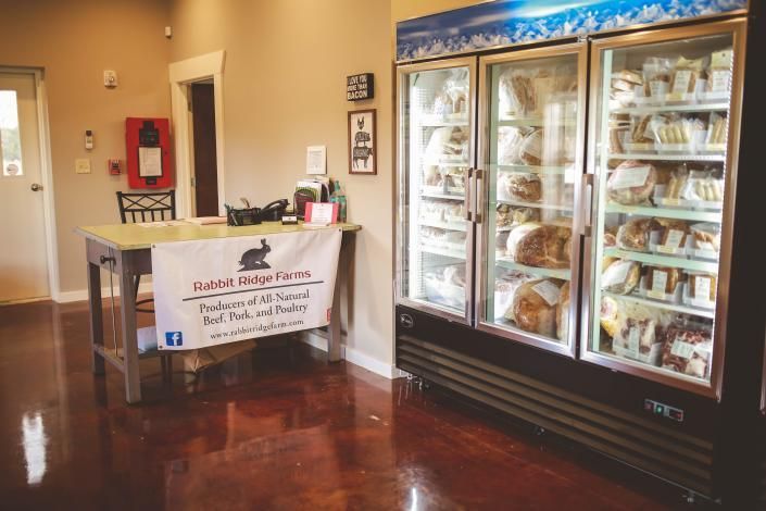 Lobby with a donation table beside a glass-front freezer stocked with packaged meals.