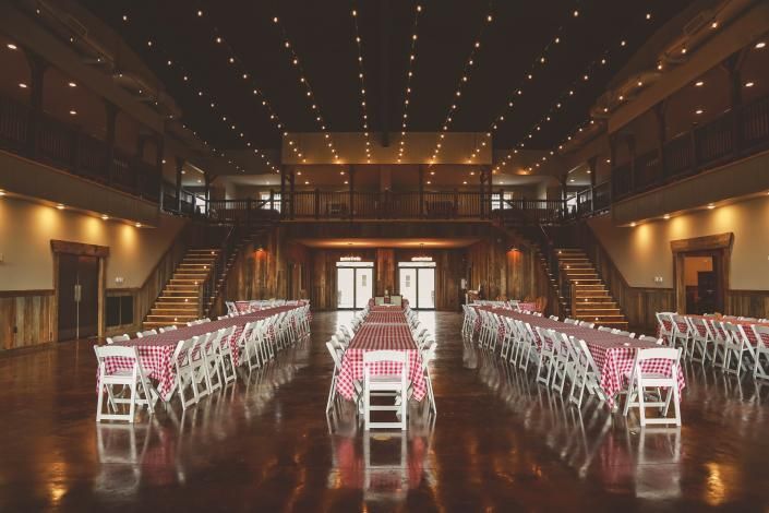 Elegant banquet hall with rows of white chairs and pink bows on a polished wooden floor