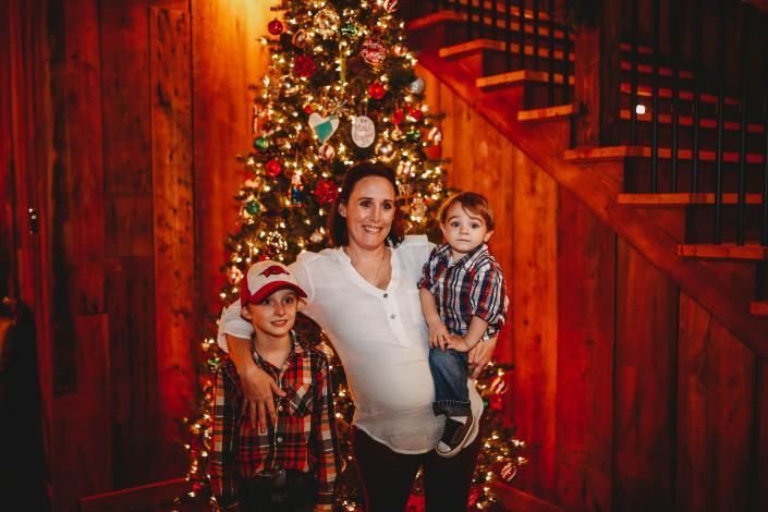 Family posing by a decorated Christmas tree in a warmly lit home staircase area